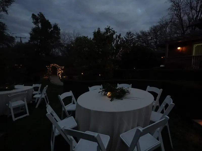 Backyard round table under string lights at dusk at a Sausalito houseboat-district party