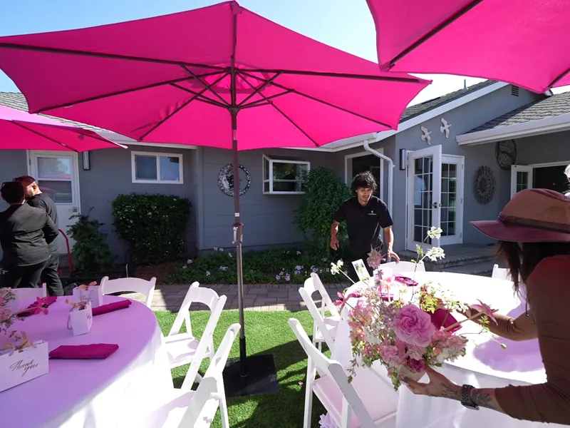 Floral centerpiece on an umbrella table with staff nearby at a Petaluma farmhouse dinner