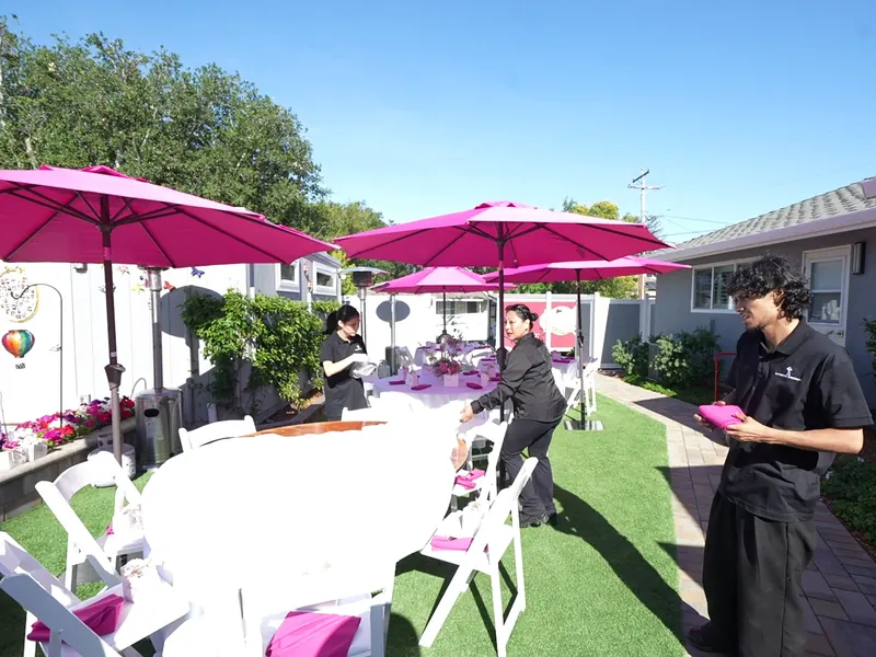 Attendant crossing the lawn between umbrella-shaded tables at a Sausalito engagement party