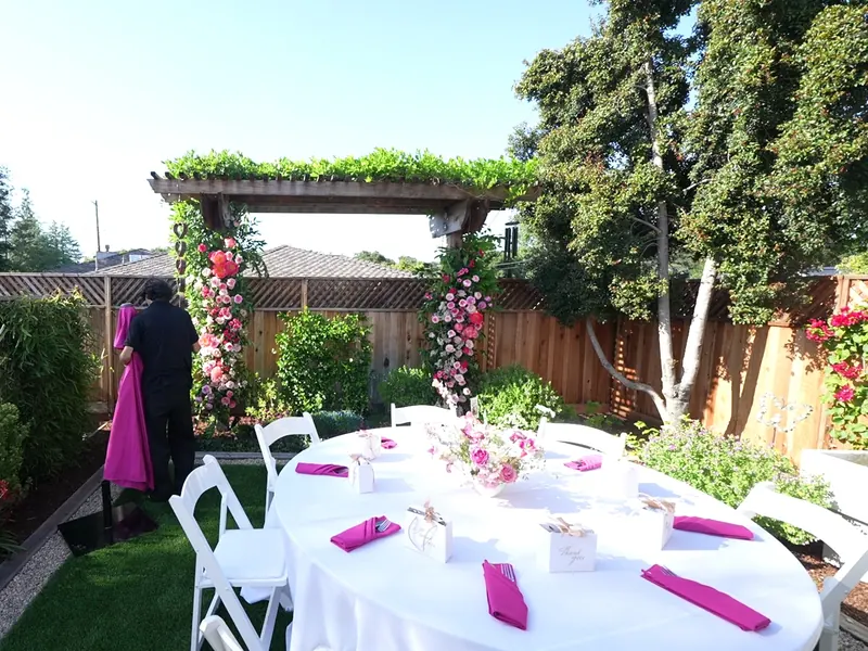 Garden floral arch with white chairs and a set dinner table at a Rohnert Park office celebration