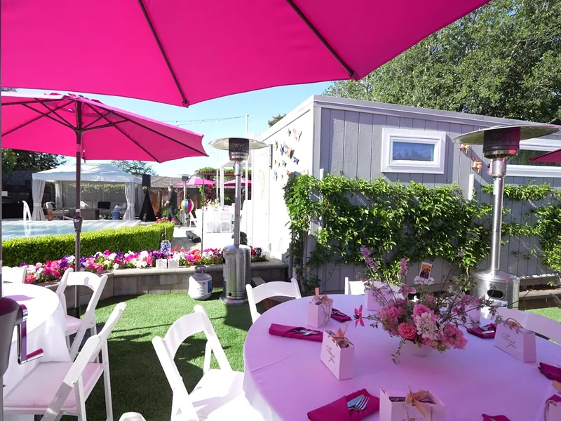 Umbrella-shaded tables set with linens on a lawn at a Santa Rosa family celebration