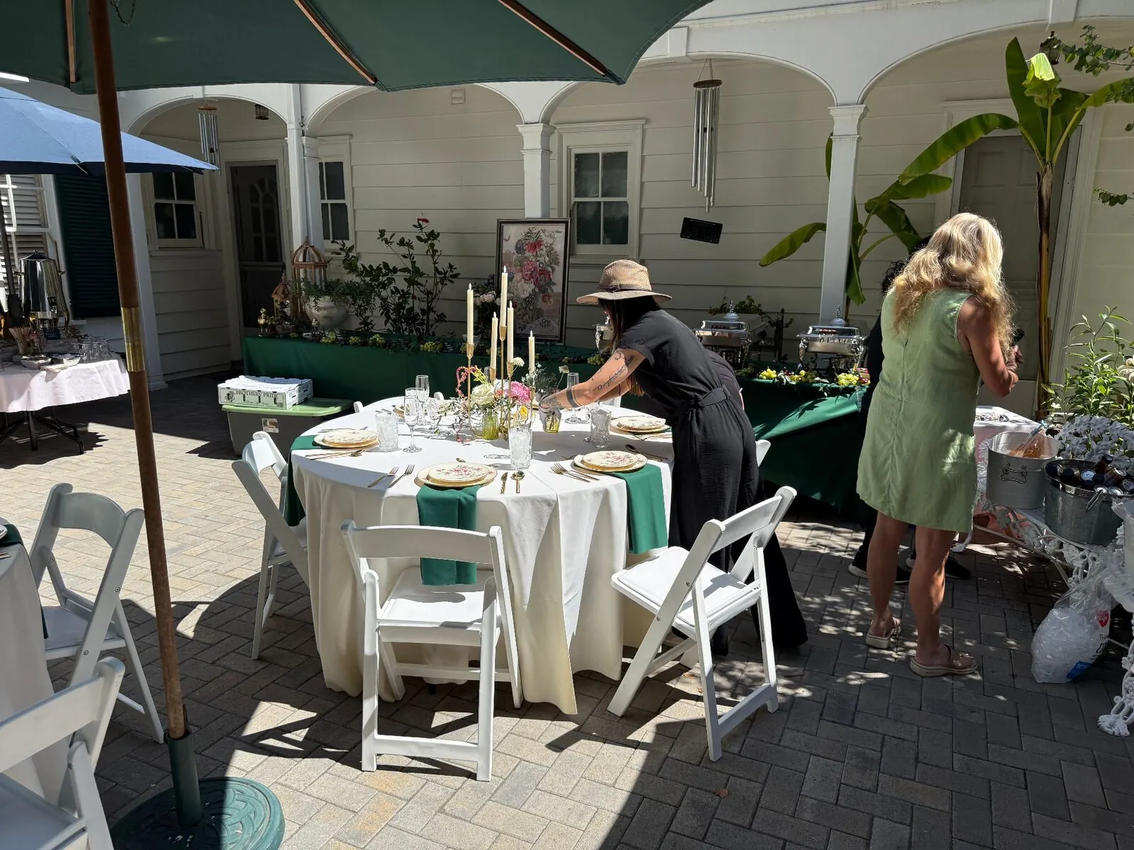 Courtyard rounds in emerald linens finished with compact centerpieces, stemware and full place settings — floral and rental styling from Marin catering