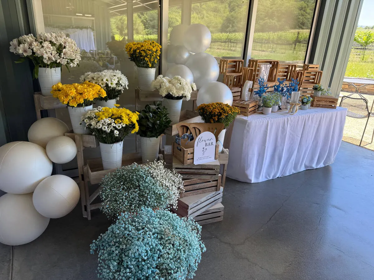 Bloom bar stocked with yellow roses, daisies and baby's breath alongside ribbon and paper for guests to wrap their own bouquets — bloom bar experience from Marin catering