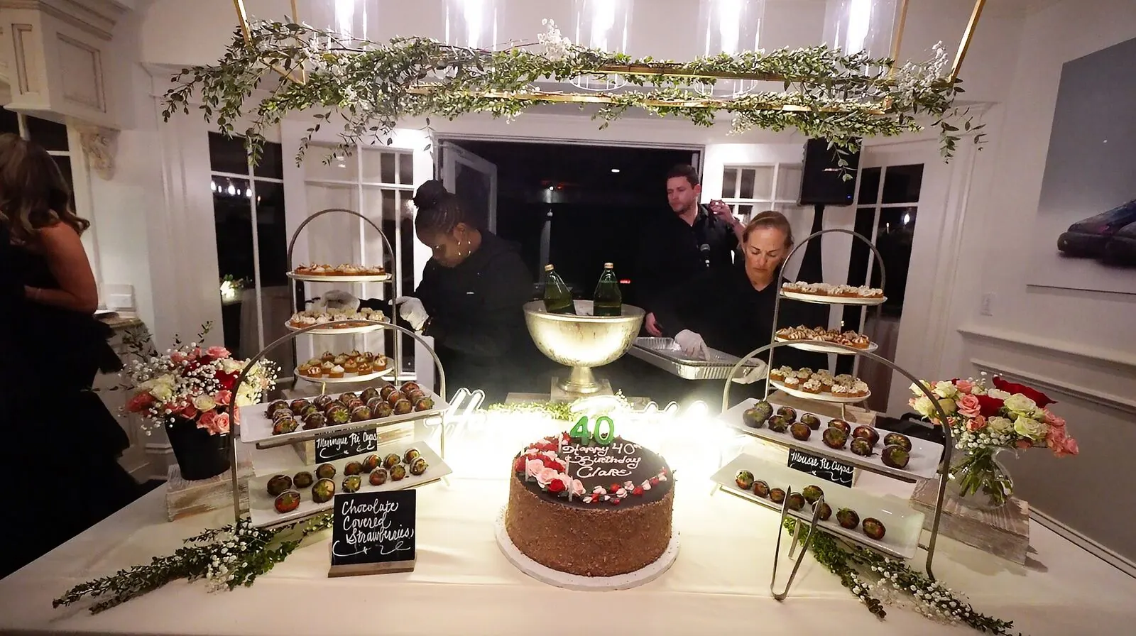 Dessert table of dipped strawberries, layered cake and petite sweets accented with fresh blooms on tiered risers — floral dessert styling for San Rafael catering