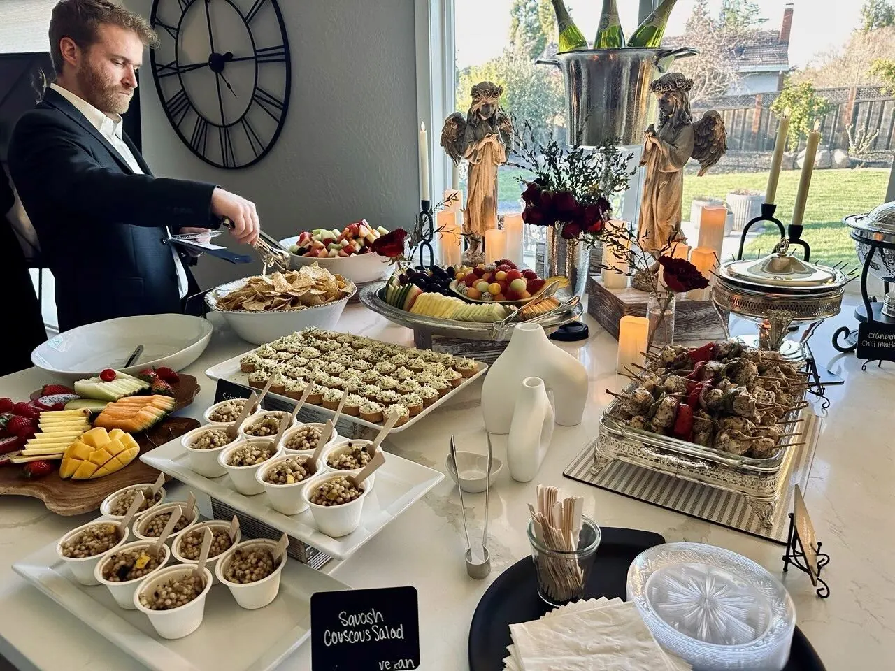 Refined starter buffet pairing herbed couscous salad, a fanned seasonal fruit platter and grilled skewers on crisp white linen — corporate starters from Marin catering