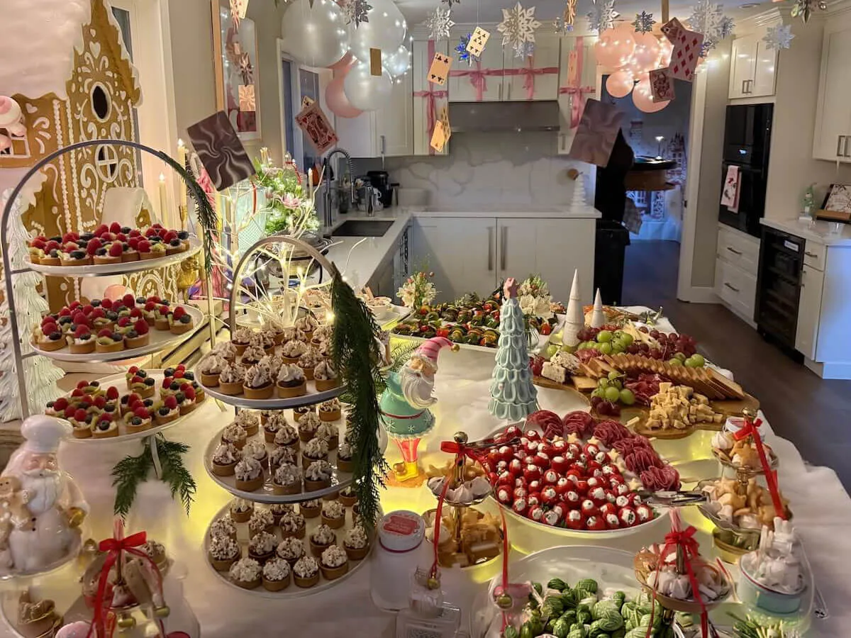 Themed party tablescape where tiered tarts and cupcakes sit beneath pastel balloons with fresh blossom accents tucked in — floral party styling for Petaluma catering celebrations